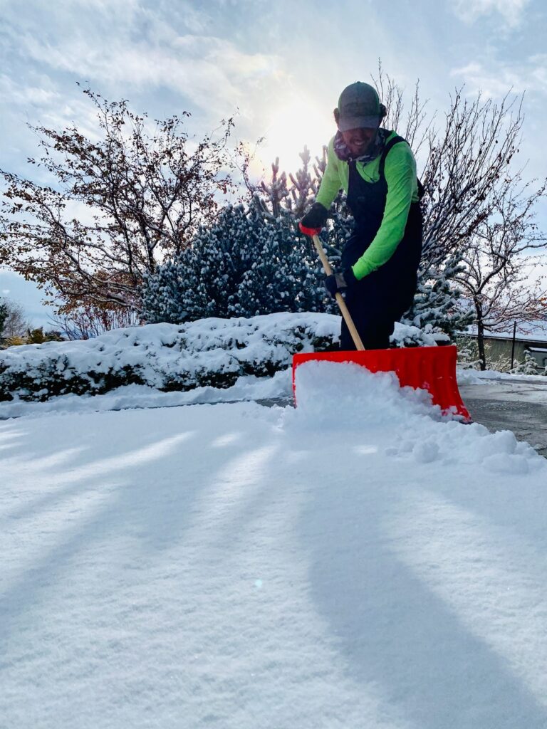 Snow removal crew member shoveling a driveway in Reno