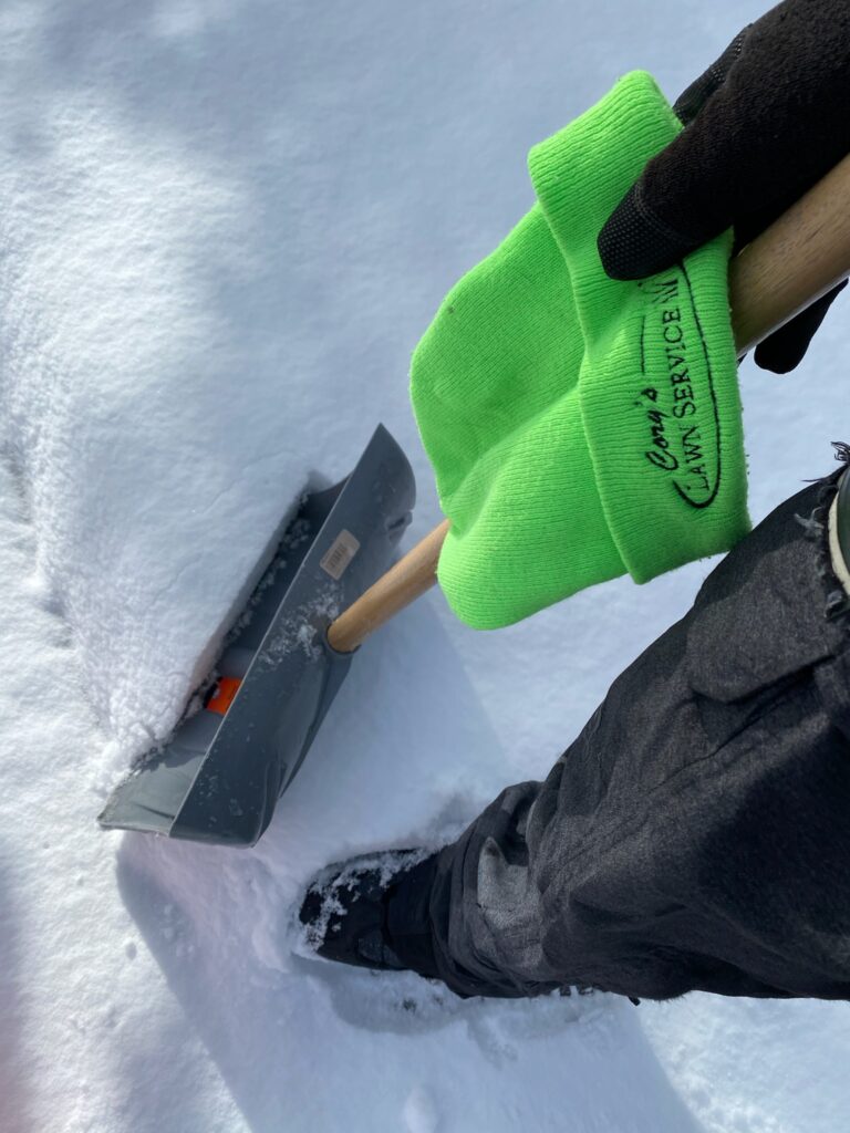 Cory's Lawn Service crew member shoveling fresh snow