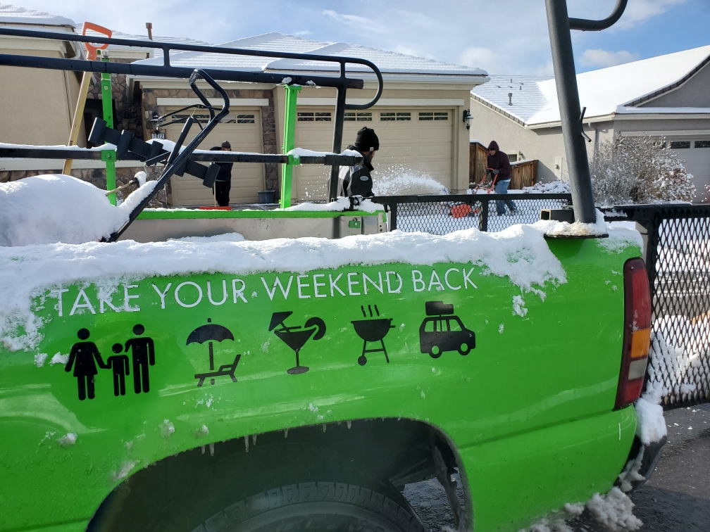 Green lawn service truck parked in fresh snow